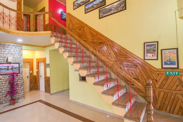 Una escalera con barandillas rojas y un pasamanos de madera, que lleva a un piso superior.