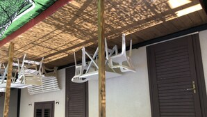 Una stanza con soffitto in legno, due porte marroni e sedie di plastica bianca appese al soffitto.