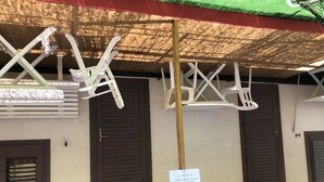 Una stanza con soffitto in legno, poltrone sospese bianche e un cartello che indica un'area riservata.