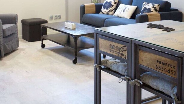 Un salon moderne avec un canapé, une table basse et une table originale à structure métallique, portant une étiquette.