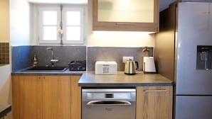 Een moderne keuken met houten kastjes, een roestvrijstalen koelkast, een inbouwvaatwasser en een raam met uitzicht.