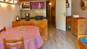 Kompakti keittiö, jossa on ruokapöytä, puukaapit ja mikroaaltouuni.
