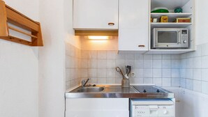 Una cocina compacta con lavabo, estufa y lavavajillas.