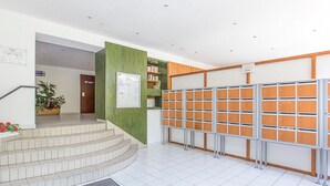 Un vestíbulo moderno y luminoso con una escalera, una pared de acento verde, un tablón de anuncios y una fila de taquillas.