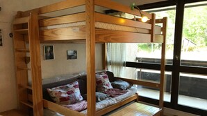 Un lit superposé avec une structure en bois, une petite table et un banc.