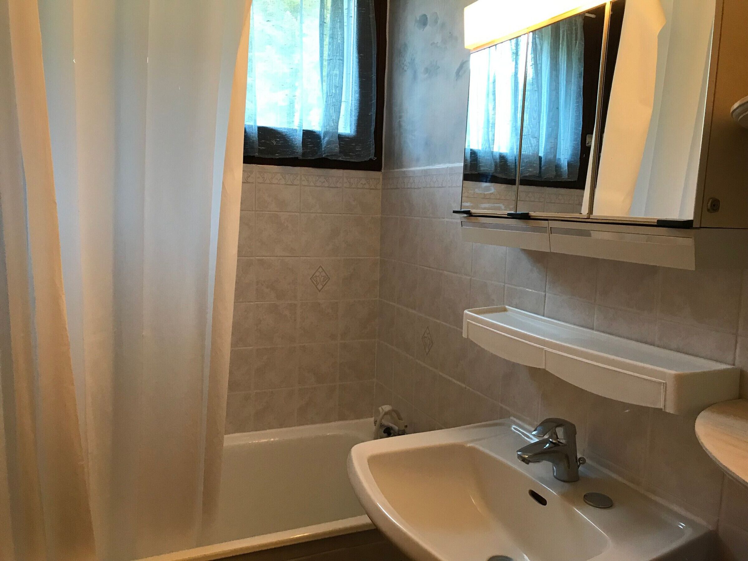 A bathroom with a bathtub, a sink, and a mirror above the sink.