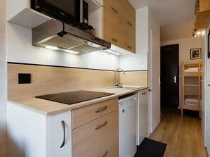A modern kitchen with a built-in stove, a sink, and wooden cabinets.