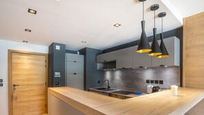Una cocina moderna con encimera de madera, armarios grises e iluminación colgante.
