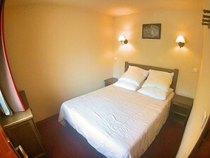 A hotel room with a bed, two bedside lamps, a nightstand, and a wall-mounted artwork. - Charming 1BR Apt with Pool, Parking and Pets Allowed in Vars Les Claux (Vars)