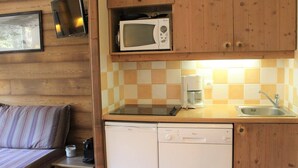 Een kleine keuken met een magnetron, koffiezetapparaat en vaatwasser.