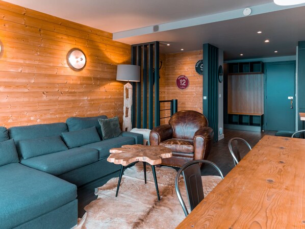 Un salon moderne comprenant un canapé, un fauteuil en cuir, une table basse en bois et une table à manger.