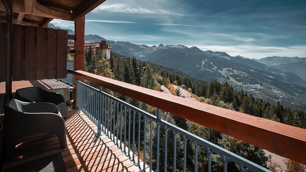 A balcony with a view of mountains, a wooden ceiling, and a railing.