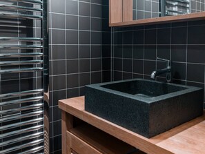 Une salle de bain moderne avec un lavabo rectangulaire noir, un robinet chromé et un meuble-lavabo en bois.