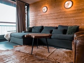 Un salon moderne avec un canapé, une petite table basse en bois et un fauteuil en cuir.
