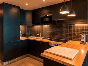 Eine moderne Küche mit dunklen Schränken, einer Holz Arbeitsplatte und einem eingebauten Ofen.