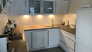 Une cuisine moderne avec des armoires blanches, un évier en acier inoxydable et un four encastré.