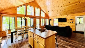 A spacious cabin with a large kitchen area, dining space, and a living area with a sofa and TV.
