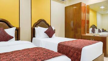 Een hotelkamer met twee bedden, een houten garderobe en een spiegel.