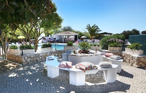 A poolside area with stone planters, white seating, and umbrellas. - ORCHARD APARTMENT  (Lagos)