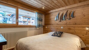 A wooden-paneled room with a bed, a window with curtains, and a wall-mounted sail decoration. - Spacious 4-room flat, 6 pers., La Clusaz, large balcony (La Clusaz)