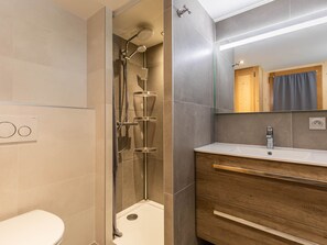 Un baño moderno con ducha, inodoro, tocador y espejo.