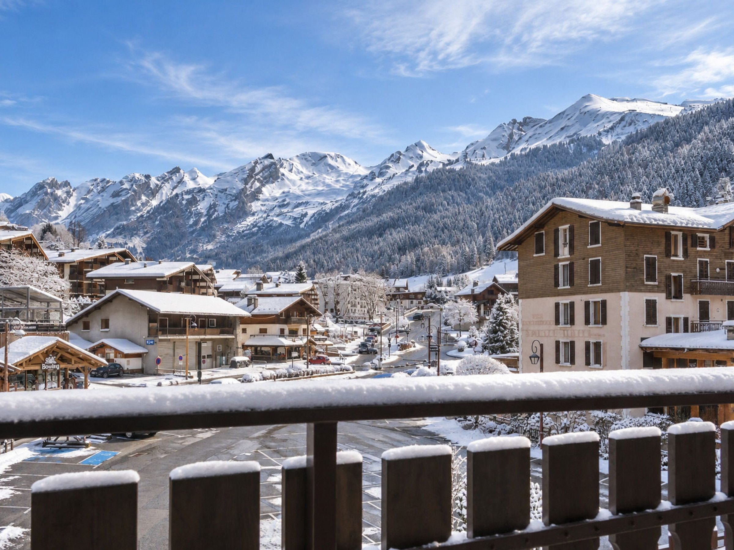 A snow-covered mountain town with wooden buildings and a clear view of snow-capped mountains in the background.