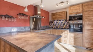 A modern kitchen with a central island, wooden cabinets, a stainless steel range hood, and a patterned backsplash. - Spacious 4-room flat, 6 pers., La Clusaz, large balcony (La Clusaz)