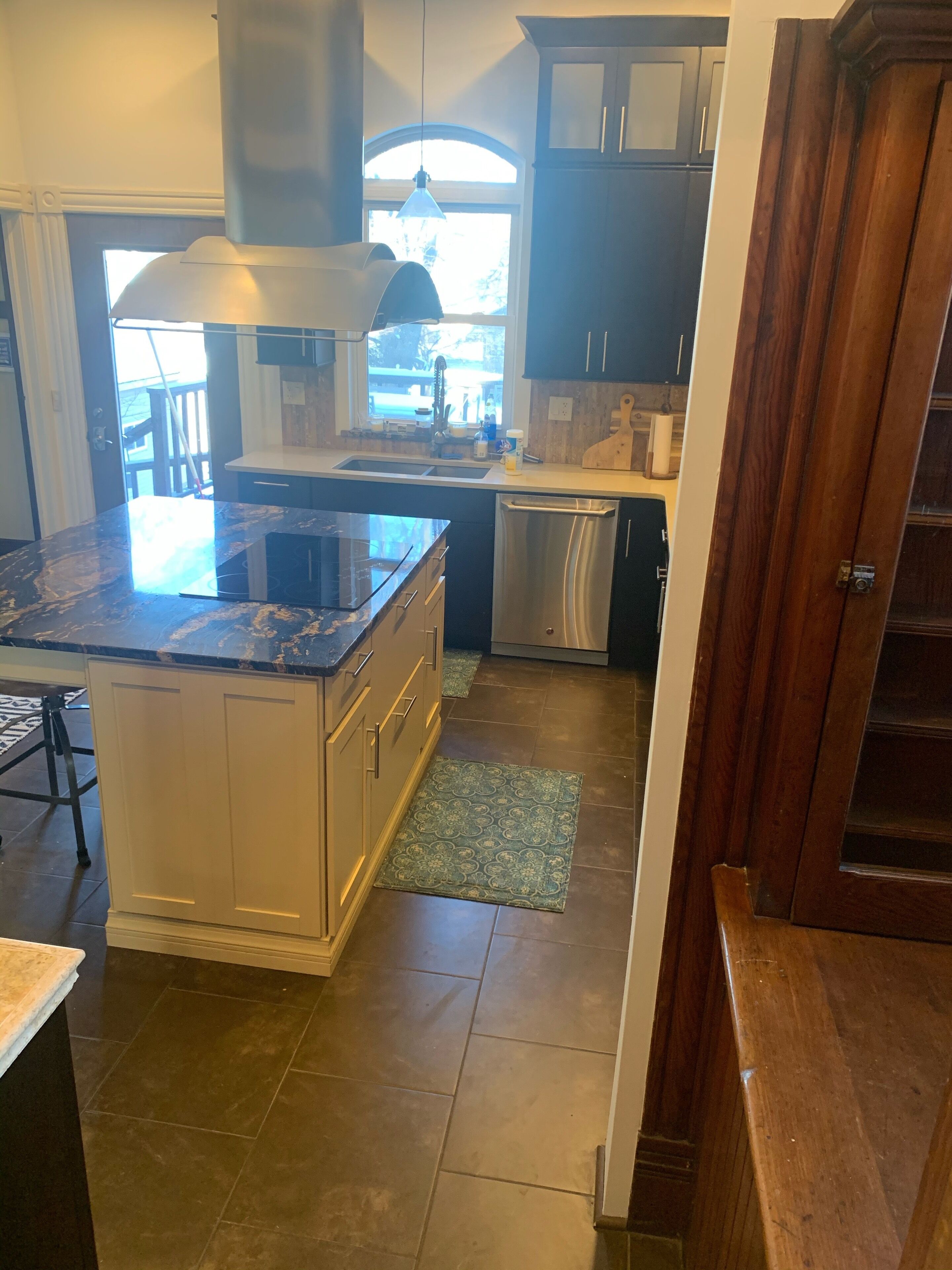 A modern kitchen with a central island, stainless steel appliances, and a view to the outdoors.