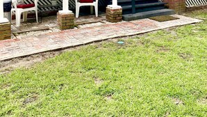 A covered patio area with brick flooring, white chairs, and a staircase leading to an upper level. - In 1840 Burn Cottage (Society Hill)