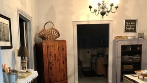A room with a wooden cabinet, a chandelier, a patterned rug, and a refrigerator. - In 1840 Burn Cottage (Society Hill)