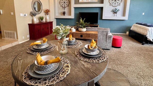 A dining area with a round table set for four, a fireplace, and a television in the background. - Prickly Pear Suite, Near Old Town (Albuquerque)
