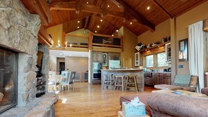 A spacious living area with a stone fireplace, wooden flooring, and a high ceiling with exposed beams. - Stonegate #14 Luxury Cabin with Hot Tub - Walking Distance to Village & Gondola! (Mammoth Lakes)