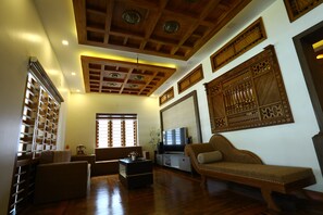 Een ruime woonkamer met een houten plafond, een televisie en een bank.