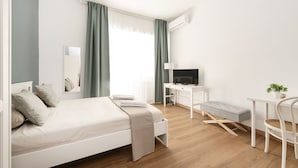 Een moderne slaapkamer met een bed, bureau, stoel en televisie.