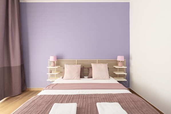 A neatly made bed with a wooden headboard, a bedside table with a lamp, and a curtain on the left. - Il Dogandiere B&B (Rome)
