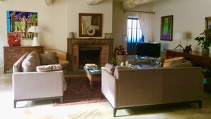 Una sala de estar con chimenea, sofás, televisión y obras de arte en las paredes.