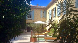 Un patio con piscina, mobiliario exterior y plantas en macetas.