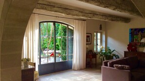 Un salón amplio con un gran ventanal arqueado, un sofá, una mesita y una planta en maceta.