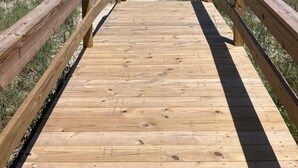 A wooden boardwalk leading to a beach with a clear view of the ocean.