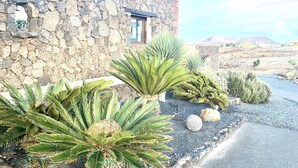 A stone building with a window and a door, surrounded by various plants. - Casa Estela, quiet house with beautiful views (Villaverde, La Oliva)