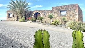 A stone building with a large arched entrance, a small window, and a door. - Casa Estela, quiet house with beautiful views (Villaverde, La Oliva)