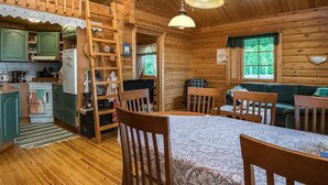 Un intérieur de chalet chaleureux comprenant un coin repas, une cuisine et une chambre à coucher située en mezzanine.