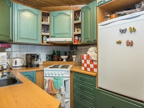 A kitchen with green cabinets, a white stove, and a refrigerator with magnets. - Hirsiniemi by Interhome (Punkaharju)