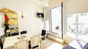 A dining area with a chandelier, a television, and a view of the outside. - Portuguese Soul Alfama | Terrace & River View | Sleeps 6 (Lisboa)