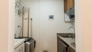 A compact kitchen with a washing machine, a sink, and a trash bin. - Altoprado Popayán (Popayán)