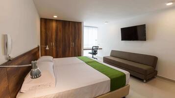 Een moderne hotelkamer met een groot bed, een slaapbank, een aan de muur bevestigde televisie en een bureau met een stoel.