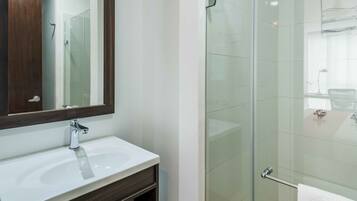 A modern bathroom with a glass-enclosed shower, a white sink, and a dark wood vanity.