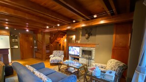A cozy living room with a blue sofa, patterned armchair, and a fireplace. - Baqueira 3 room, 4 cw spectacular duplex with parking for 6-8 people (Baqueira)