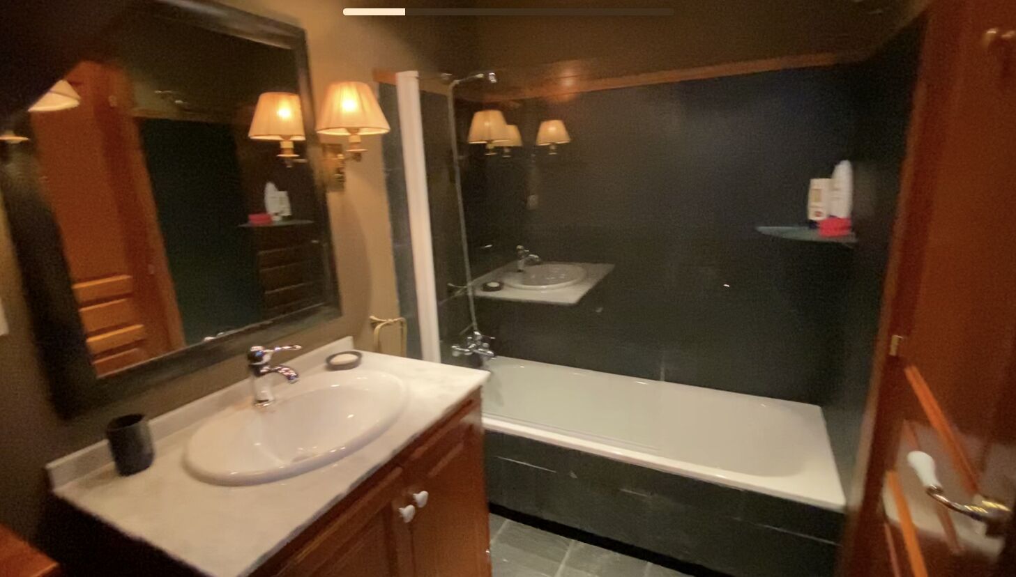 A bathroom with a sink, mirror, and bathtub.