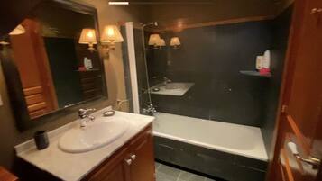 A bathroom with a sink, mirror, and bathtub.